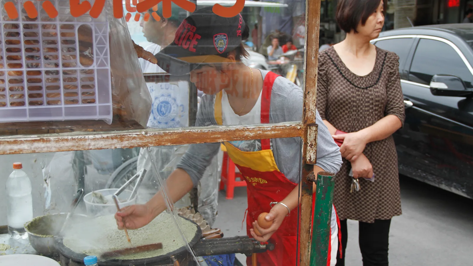 Vendor cooking a jianbing breakfast crepe on a street griddle
