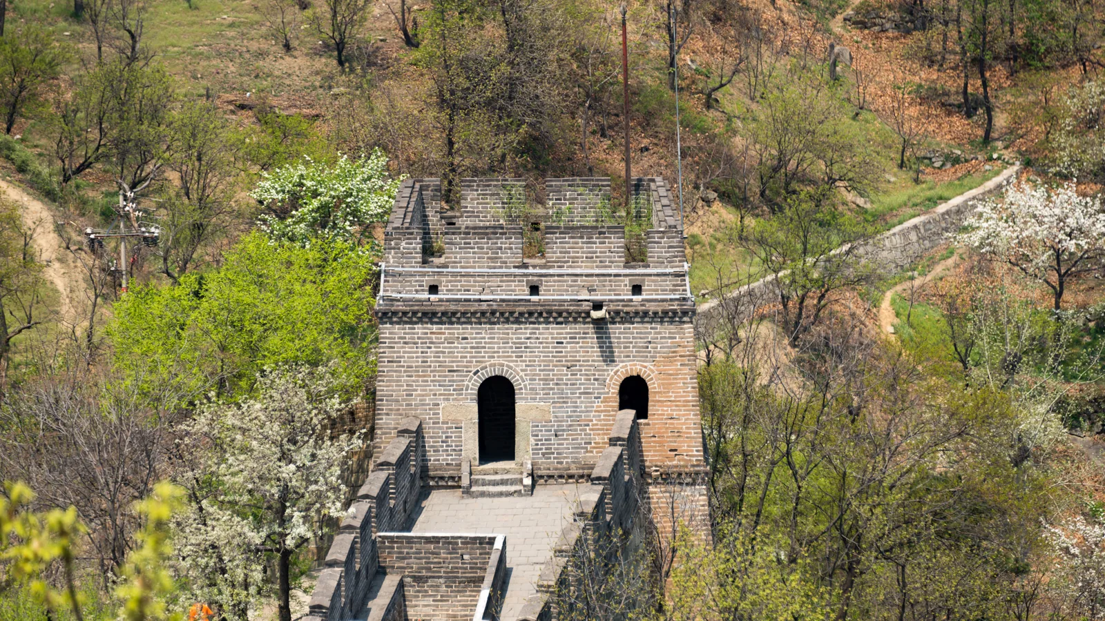 Stone watchtower and wall at Mutianyu surrounded by spring trees