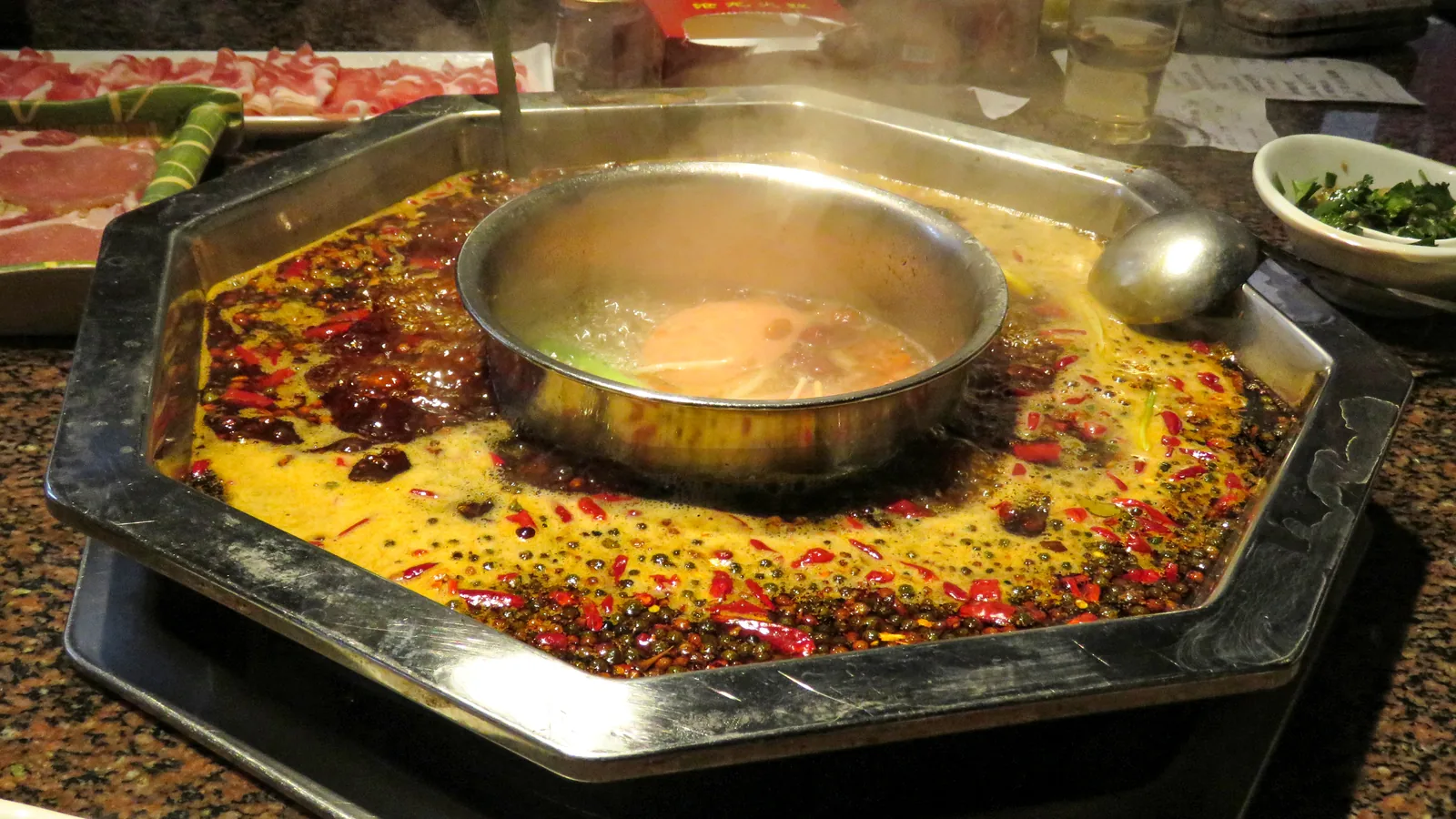 A divided Chongqing hotpot with red chili broth and a mild center broth