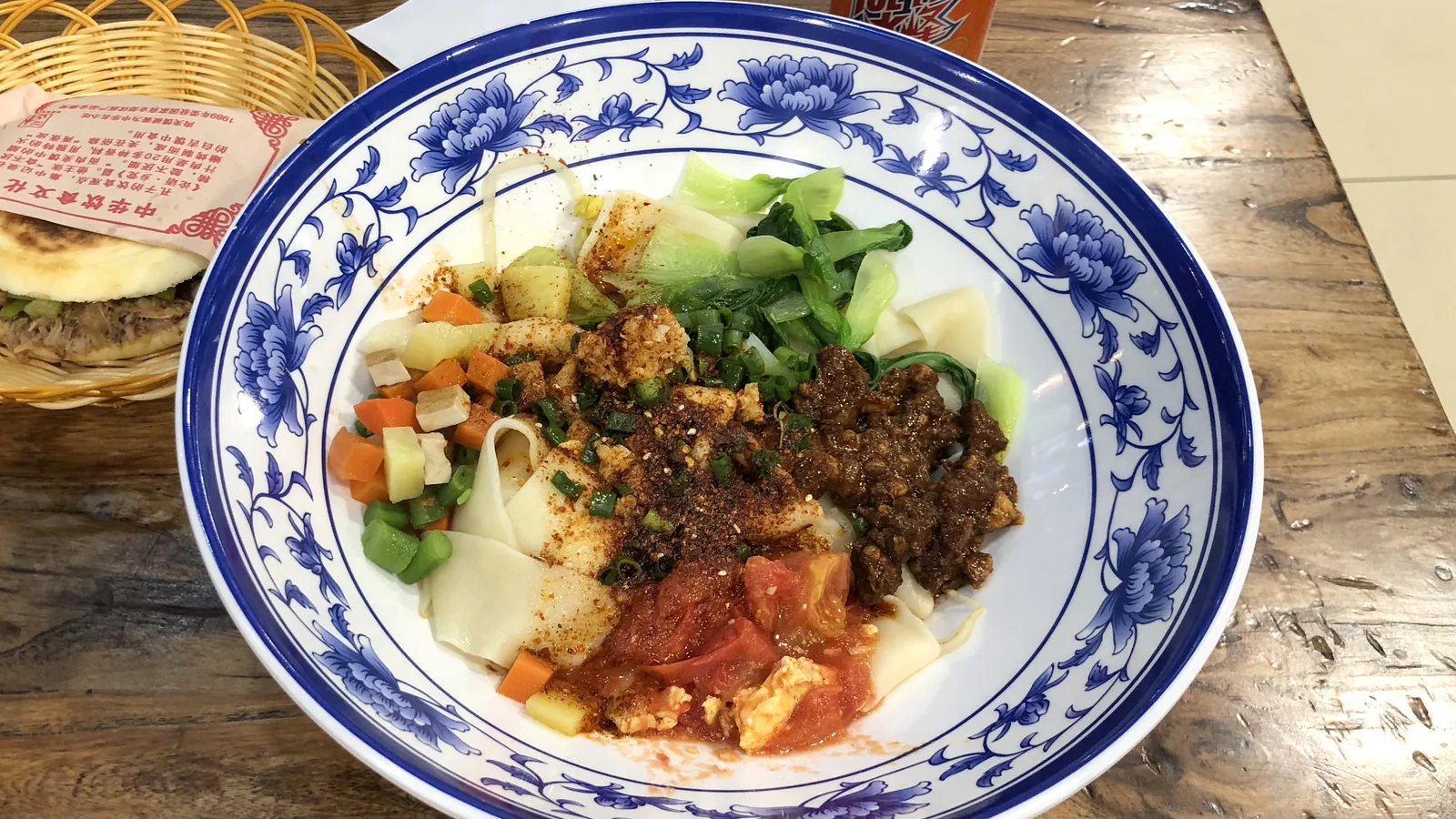 Bowl of wide hand-pulled biangbiang noodles with chili and vegetables