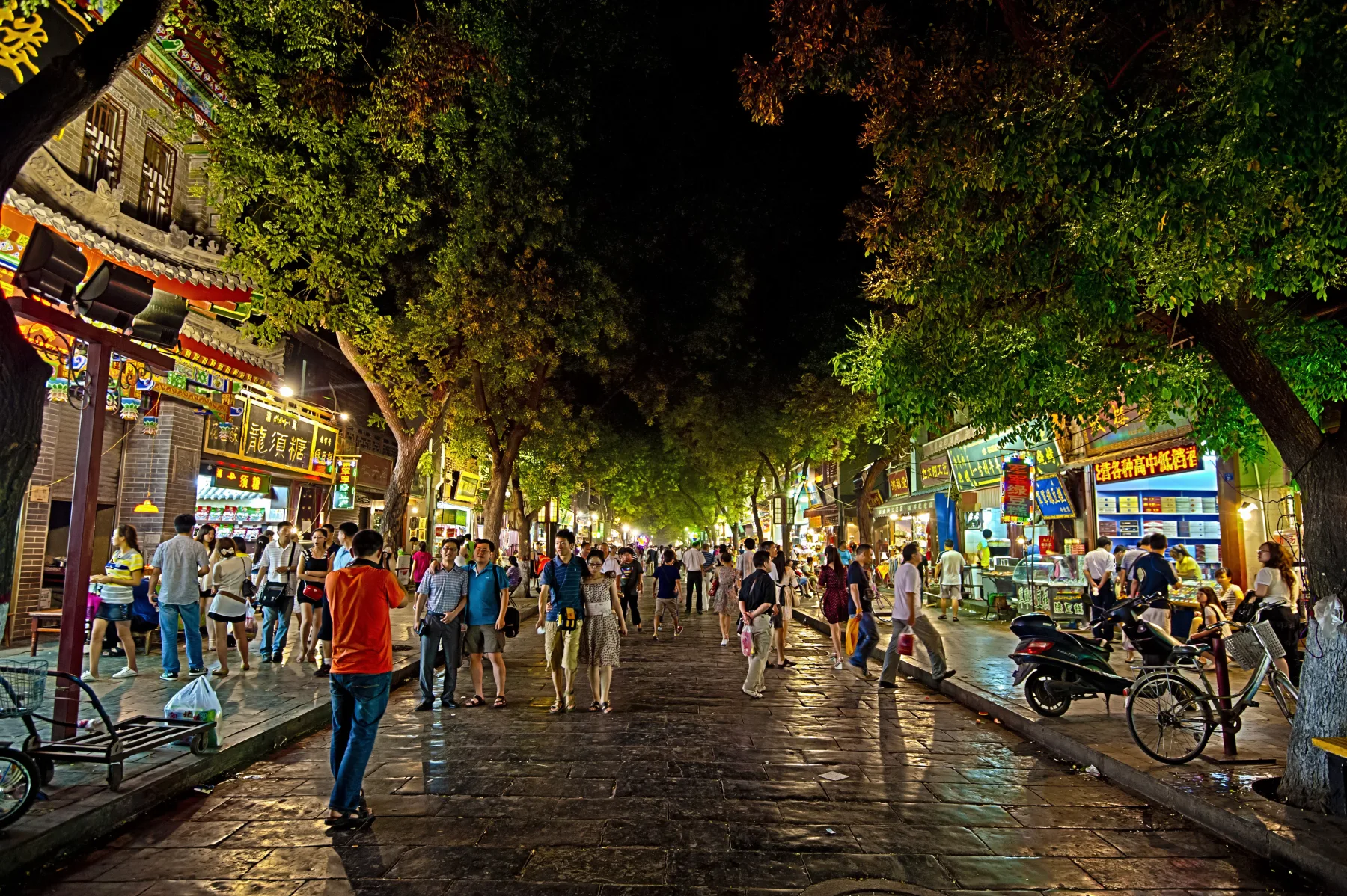 A busy tree-lined food street in Xi’an’s Muslim Quarter at night